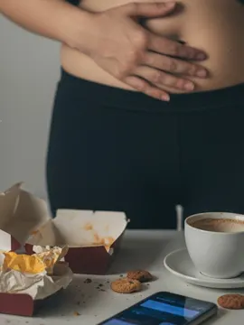 A person experiencing stomach discomfort and bloating after consuming fast food, highlighting the need for a body reset