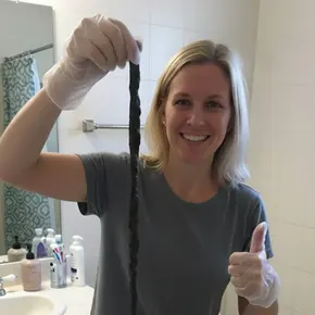 ennifer M.'s testimonial photo: Woman holding up long, old mucoid plaque, confirming the So Easy cleanse successfully pulled out 7 feet of encrusted waste that previous cleanses failed to remove